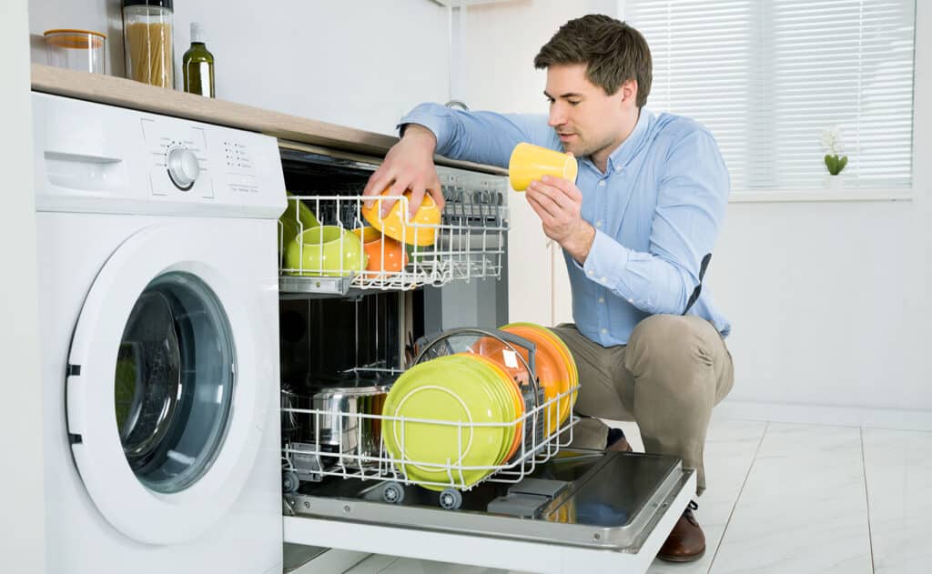 Young,Happy,Man,Arranging,Dishes,In,Dishwasher,In,Modern,Kitchen