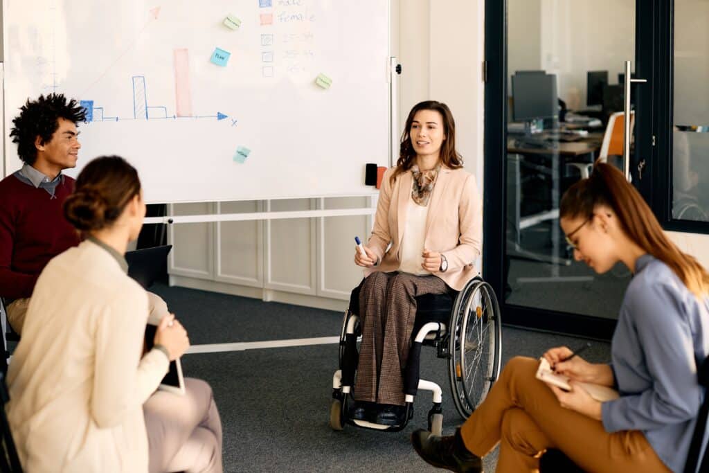 Happy,Executive,Manager,In,Wheelchair,Explaining,Her,Coworkers,Business,Strategy