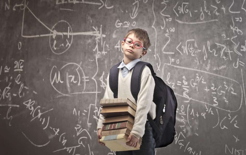 Child,With,Backpack,Holding,Some,School,Books,With,A,Blackboard