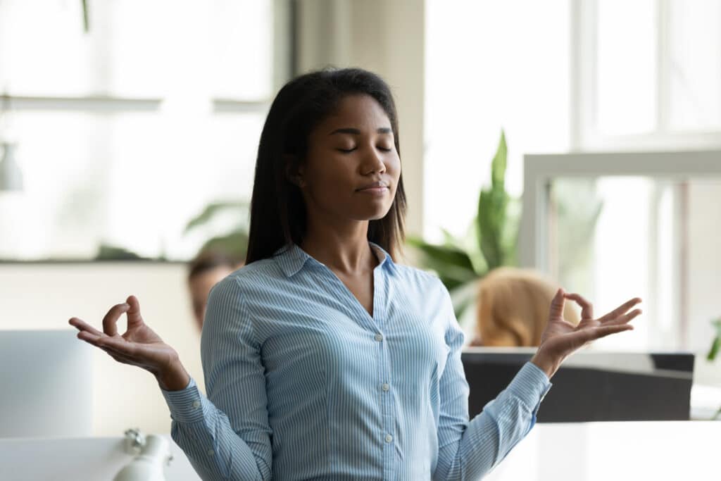 Satisfied,African,American,Businesswoman,Relaxing,,Meditating,In,Yoga,Pose,Breathing